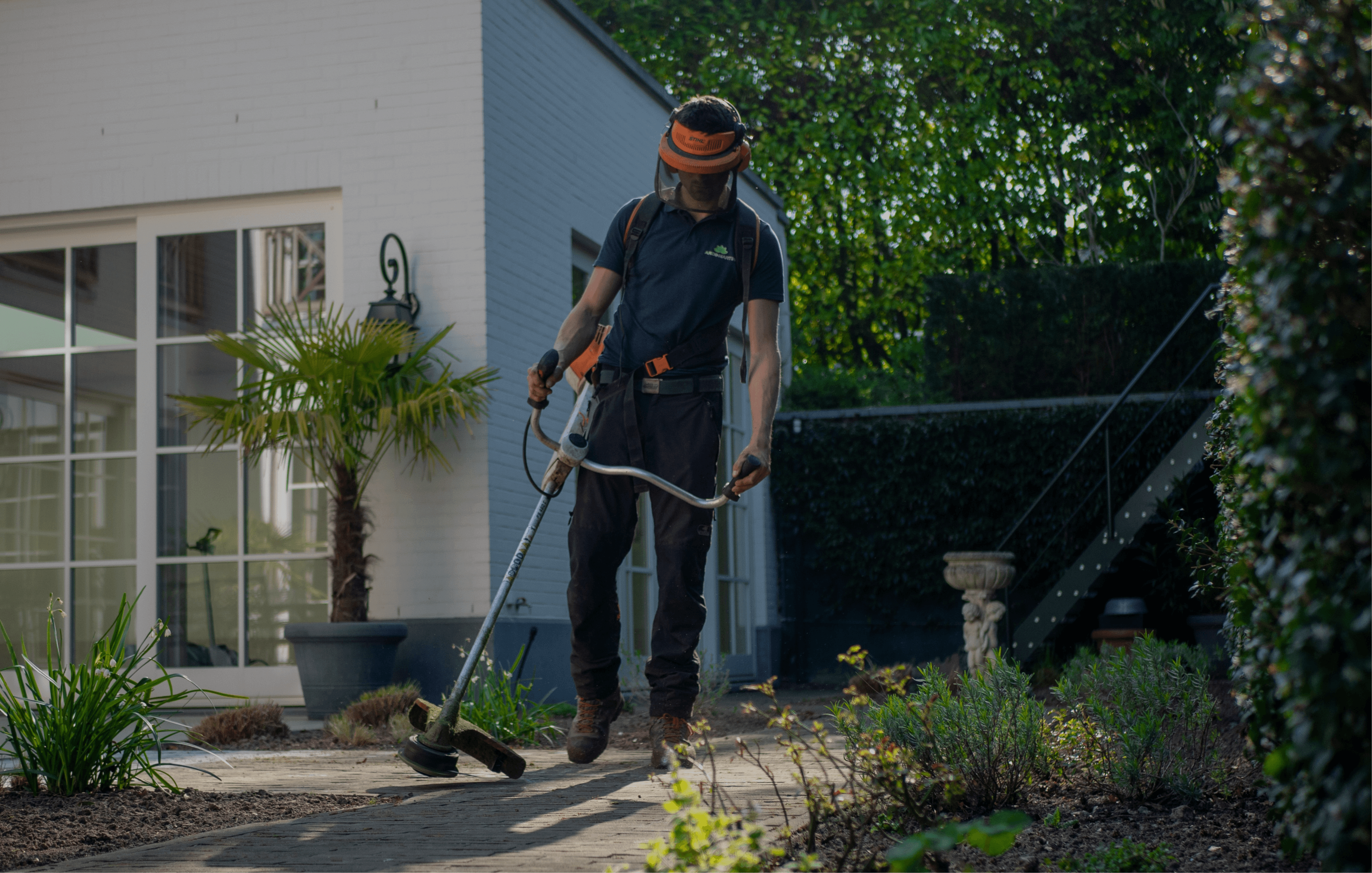 Un homme avec un débroussailleur dans une allée de jardin