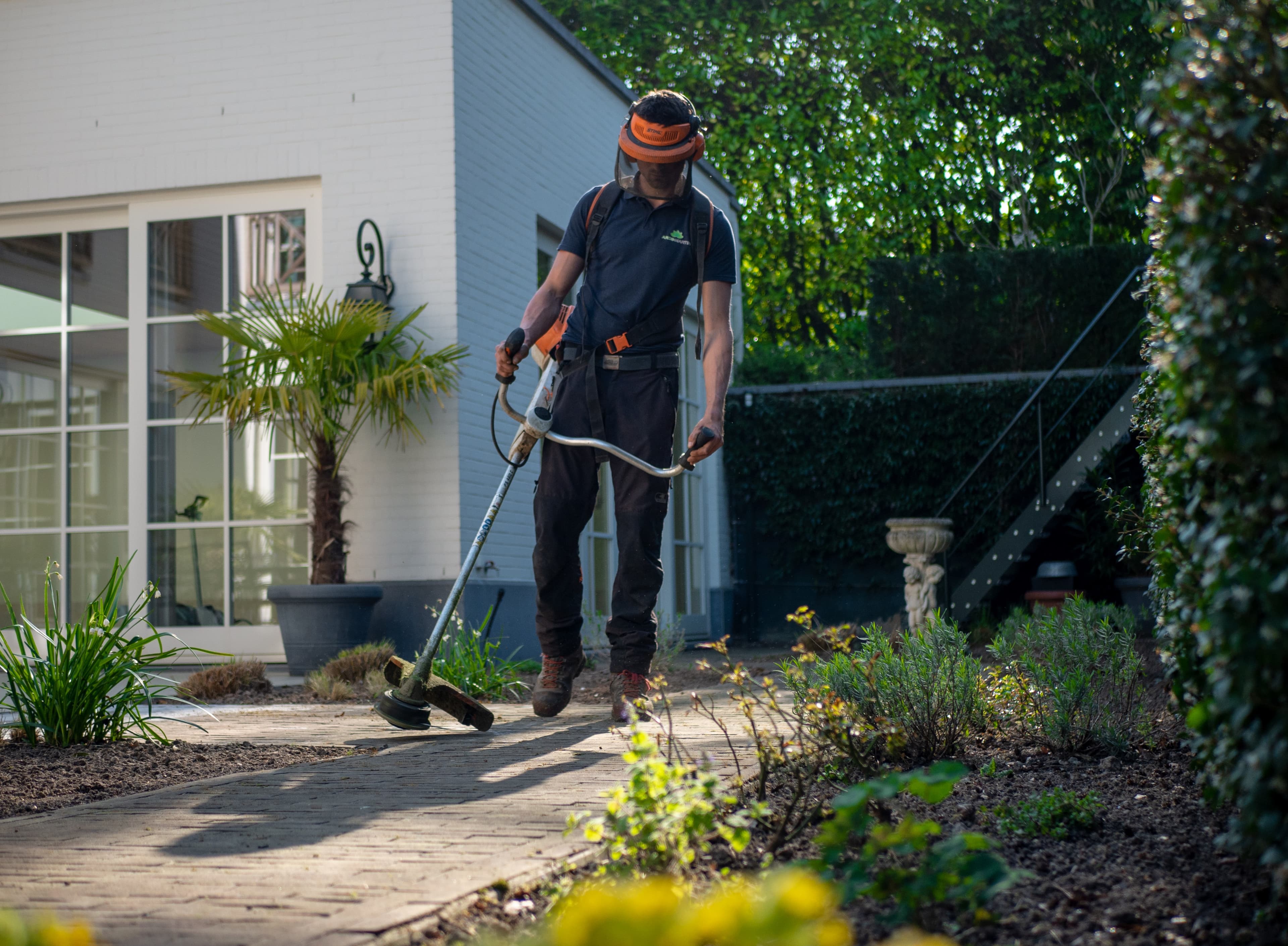 Un homme avec un débroussailleur dans une allée de jardin